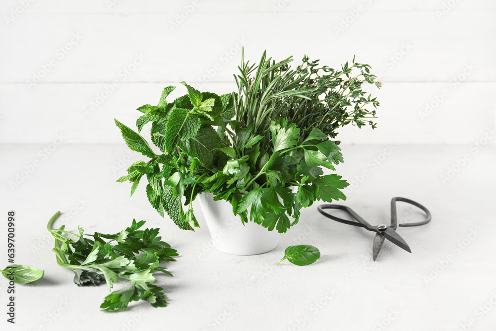 Bowl with fresh herbs and scissors on light table