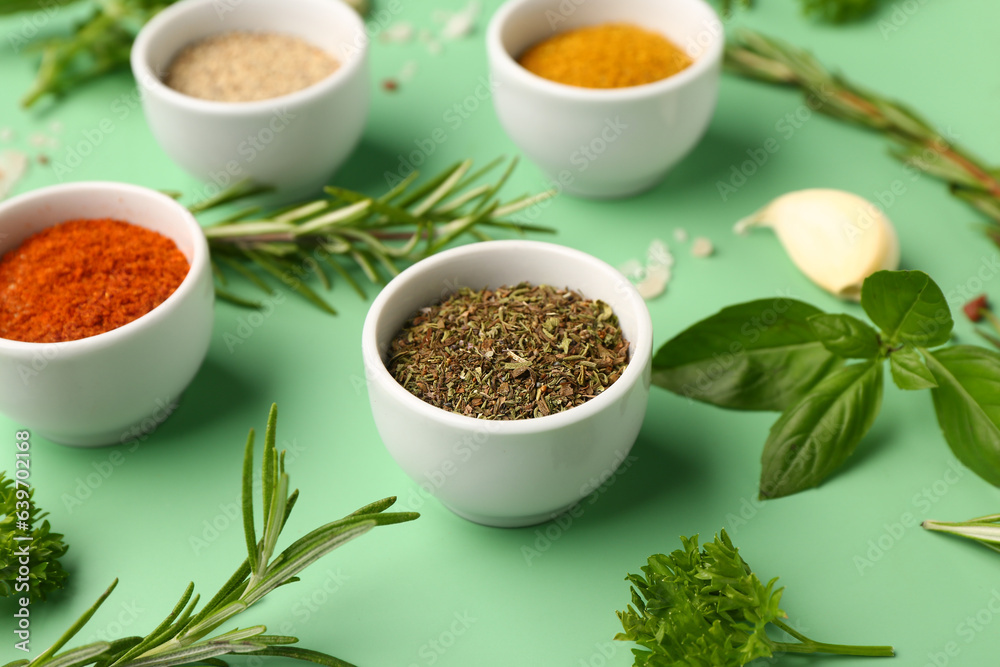 Bowls of fresh aromatic spices and herbs on color background, closeup