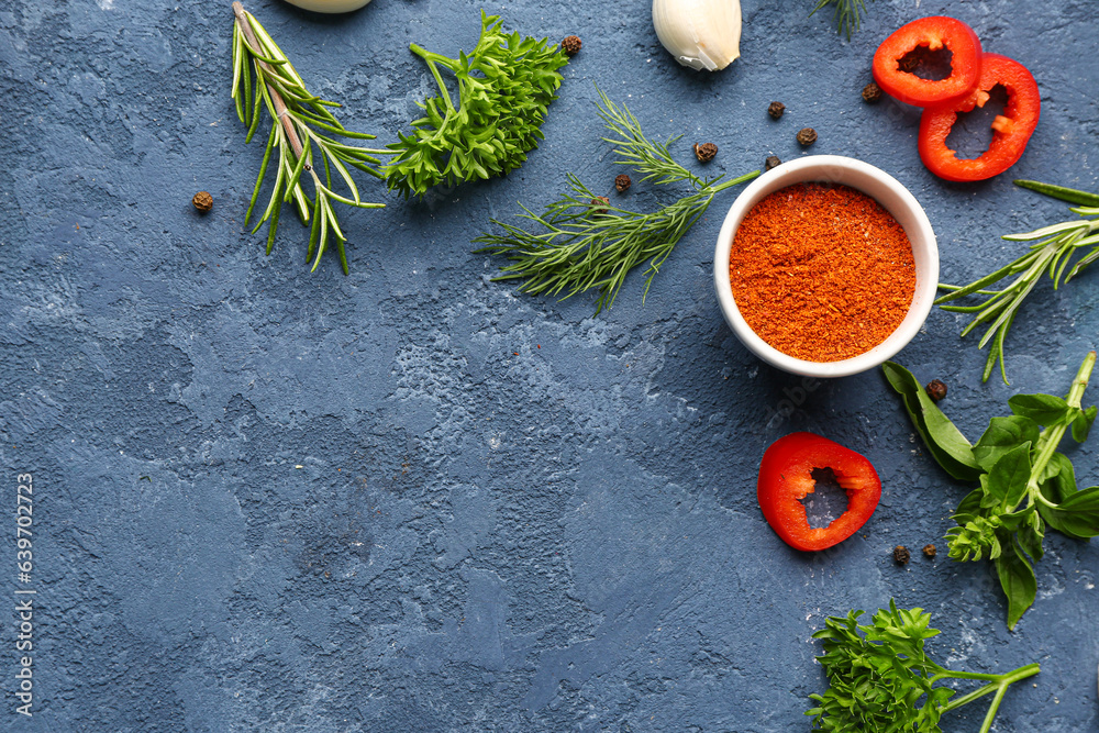 Composition with bowl of paprika powder, spices and herbs on color background