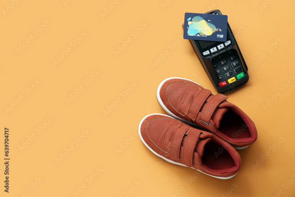Pair of stylish childs shoes, payment terminal and credit card on color background