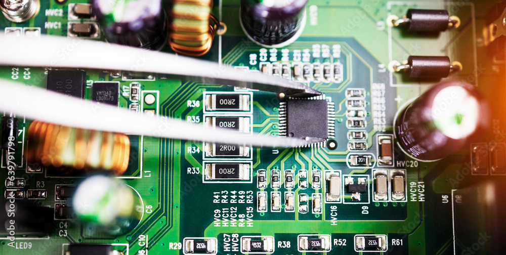 Motherboard, microchip closeup and engineering tweezer with electric maintenance of circuit board. D