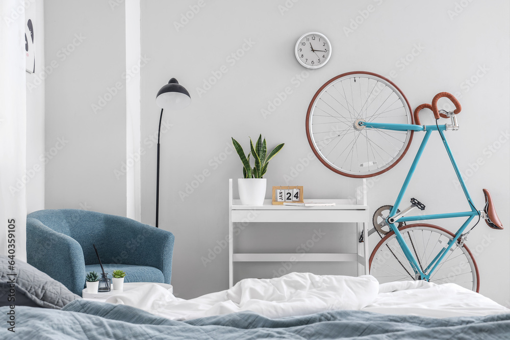 Interior of light childrens bedroom with cozy bed, armchair and bicycle