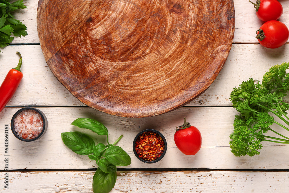 Composition with kitchen board, spices, vegetables and herbs on light wooden background, closeup