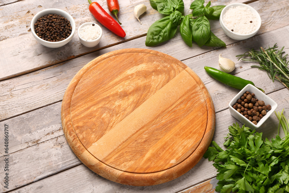 Composition with cutting board, fresh herbs and spices on light wooden background