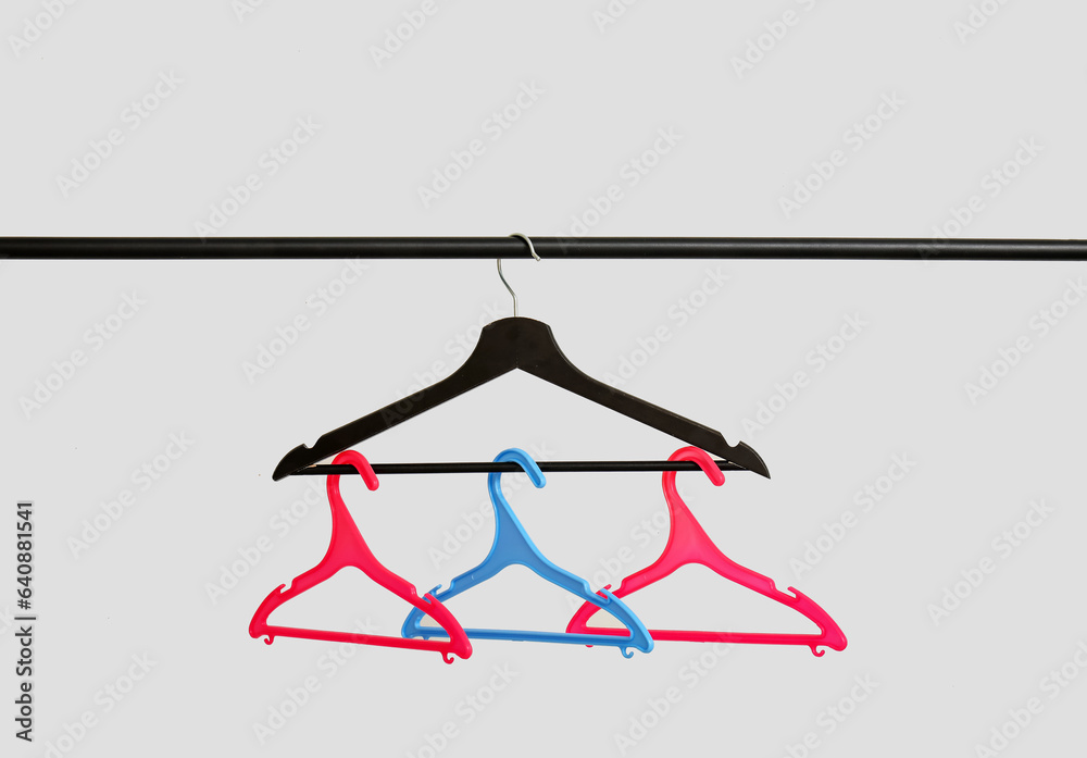Rack with plastic clothes hangers on grey background