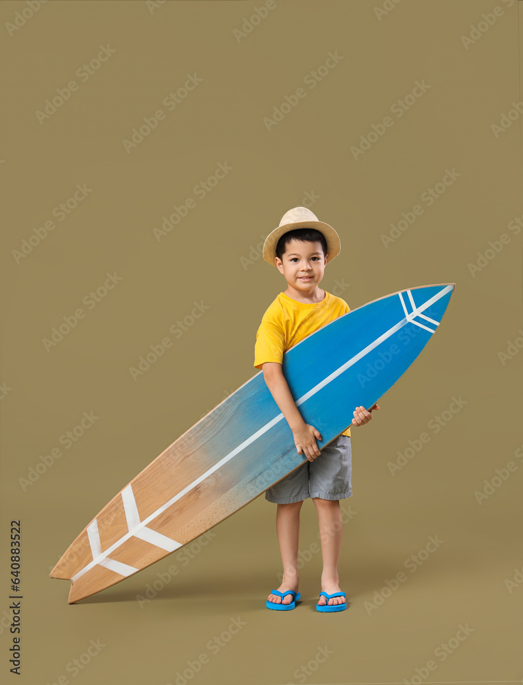 Cute little Asian boy with surfboard on green background