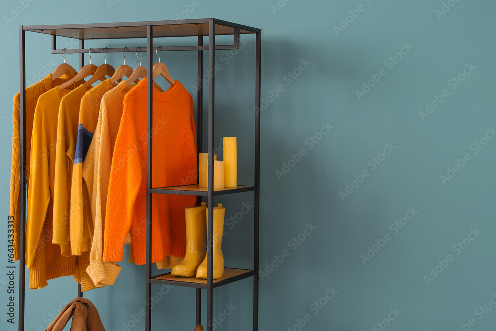 Shelving unit with clothes, candles and shoes near blue wall