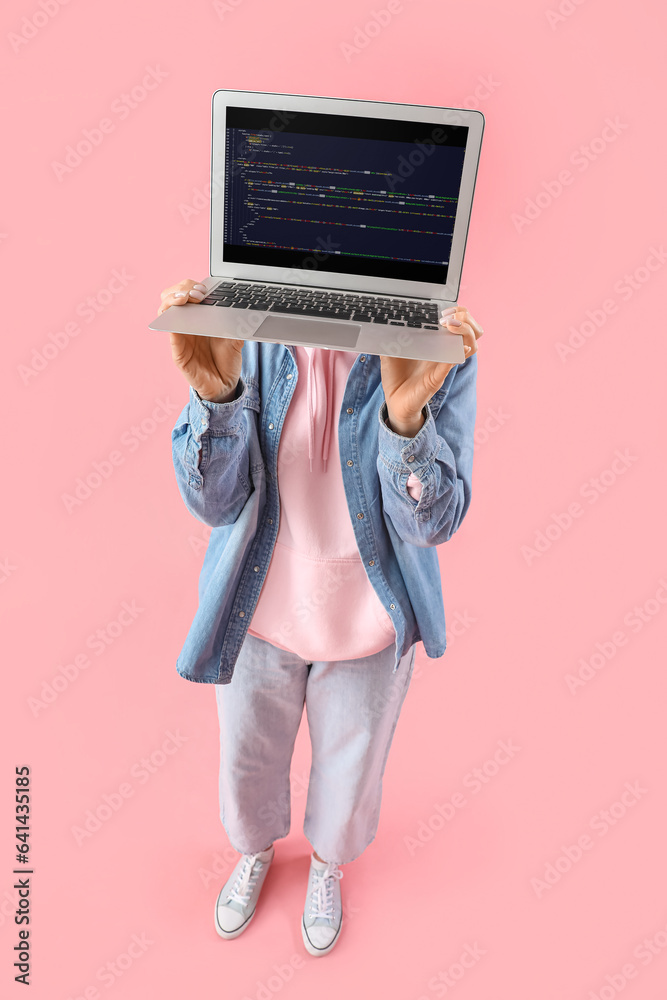 Mature female programmer with laptop on pink background