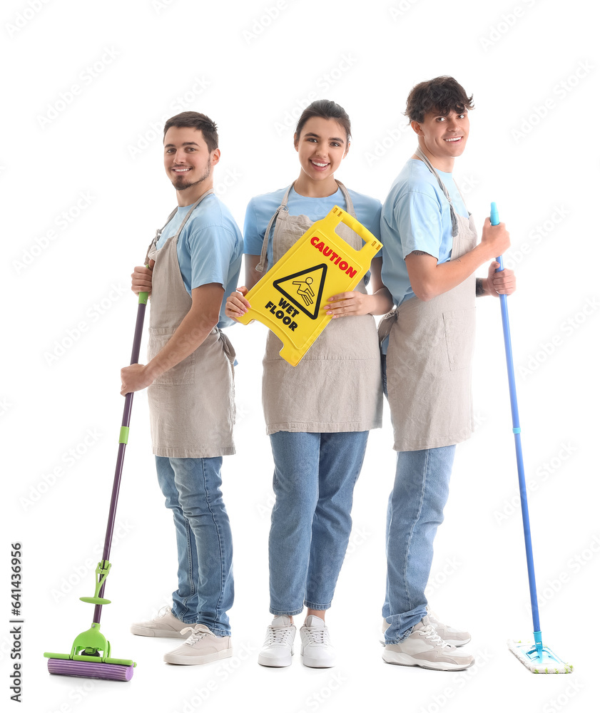 Young janitors with mops and caution sign on white background