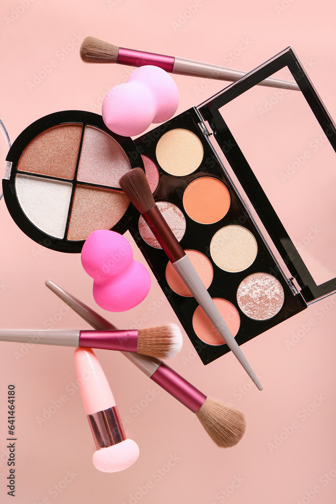 Flying makeup accessories and cosmetics on pink background, closeup