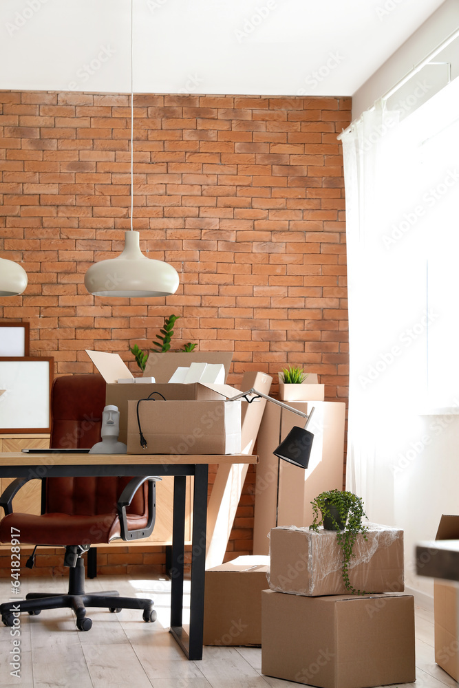 Interior of stylish office with cardboard boxes on moving day