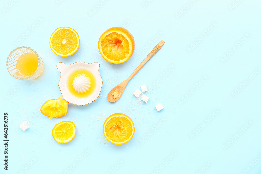 Cut orange with juicer, sugar, spoon and glass on blue background
