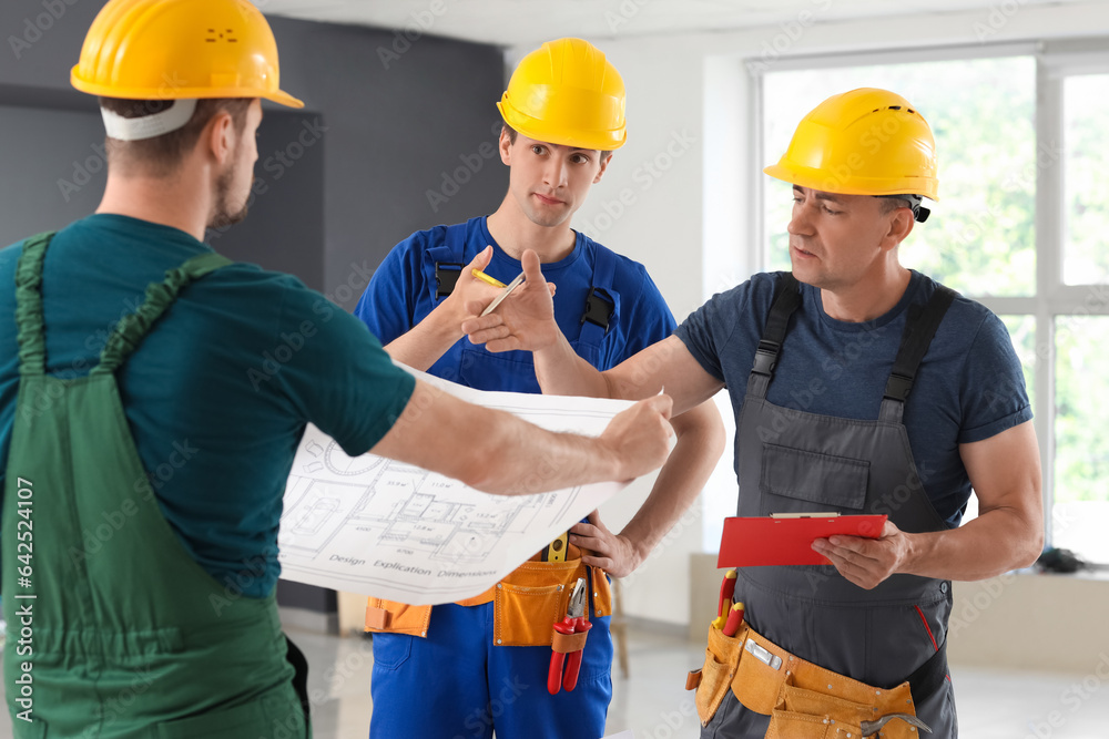 Team of male builders working with house plan in room