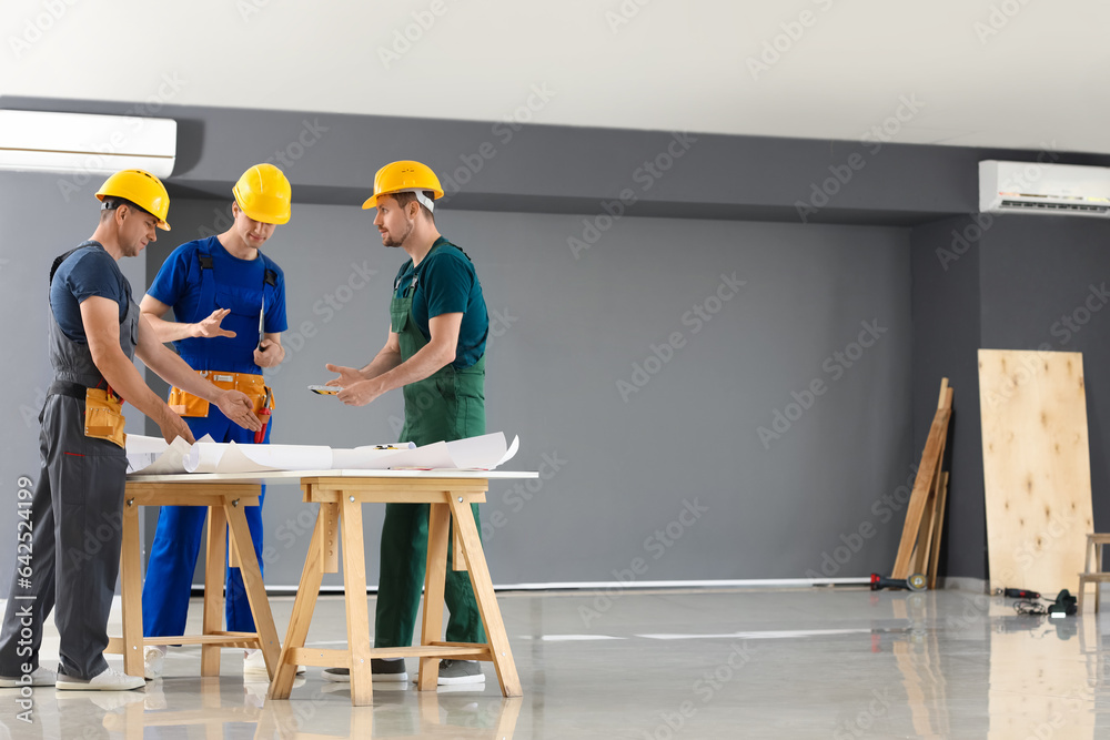 Team of male builders working in room