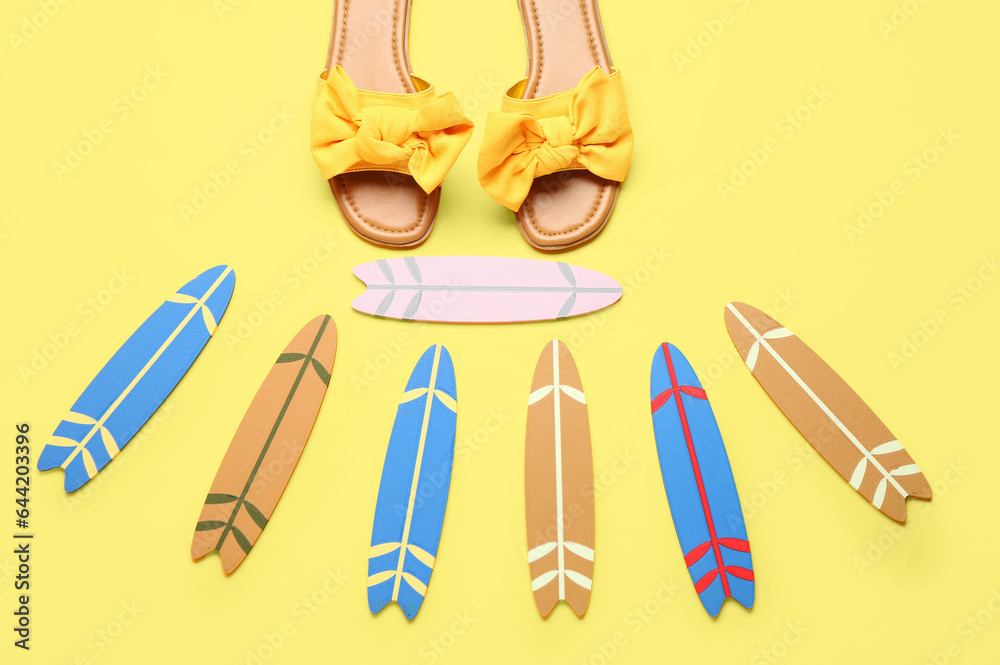Different mini surfboards and female shoes on yellow background