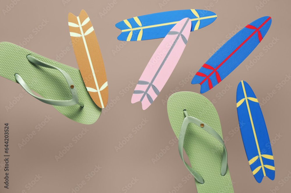 Flying mini surfboards and flip-flops on grey background