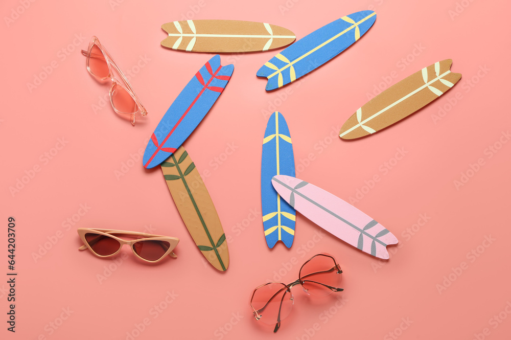 Different mini surfboards and sunglasses on pink background