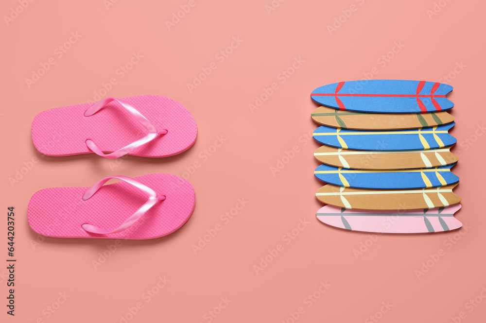 Different mini surfboards and flip-flops on pink background