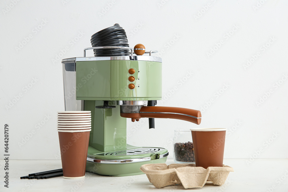 Modern coffee machine with takeaway cups and lids on white background