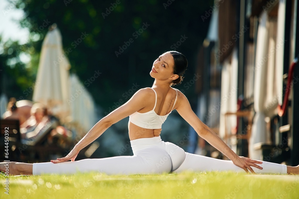 On the green grass. Young woman in yoga clothes is outdoors