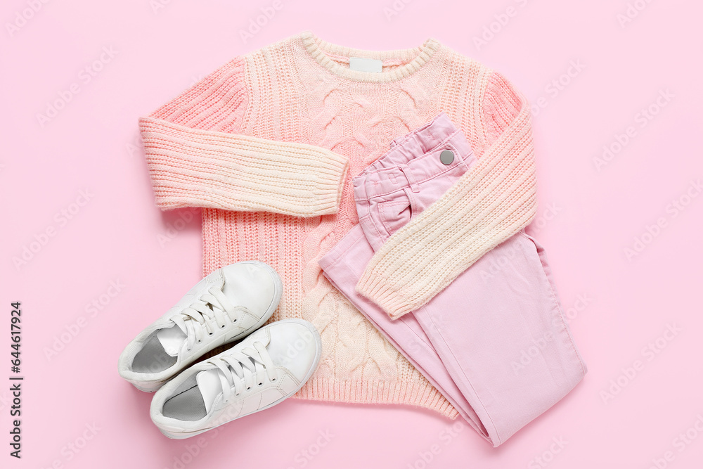 Stylish childrens sweater, pants and shoes on pink background