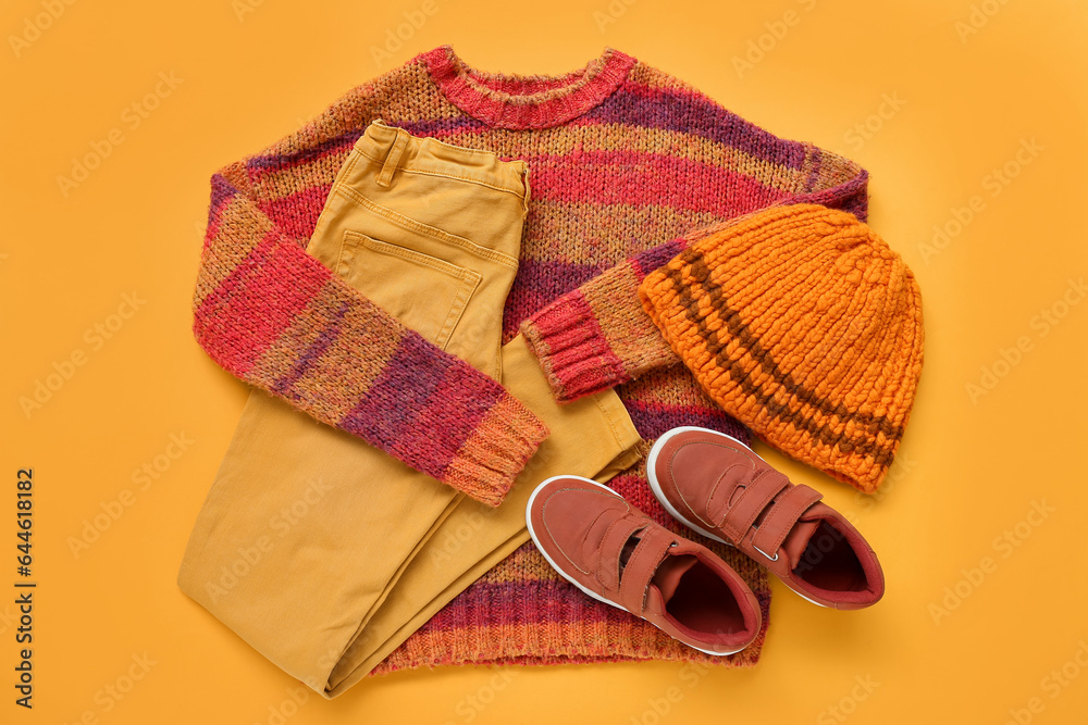 Warm childrens clothes and shoes on color background