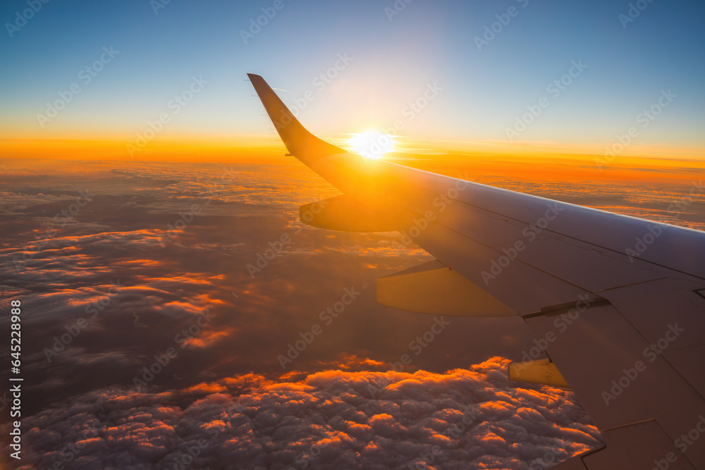Airplane flight in sunset sky over earth of city light and wing of plane. View from the window of th