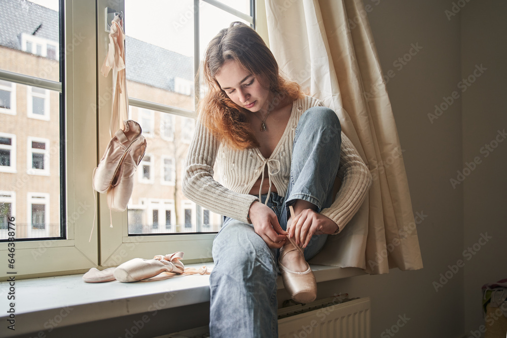Peaceful thin woman wearing training pointe shoes while relaxing at home