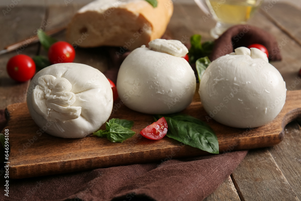 Board of tasty Burrata cheese with basil and tomatoes on wooden background
