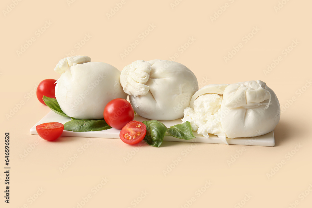 Board of tasty Burrata cheese with basil and tomatoes on beige background