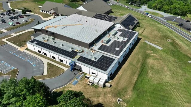 Industrial building installing solar panels with federal tax incentives in USA. High aerial birds eye view orbit.