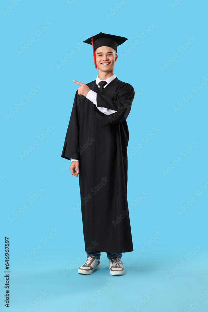 Male graduate student pointing at something on blue background