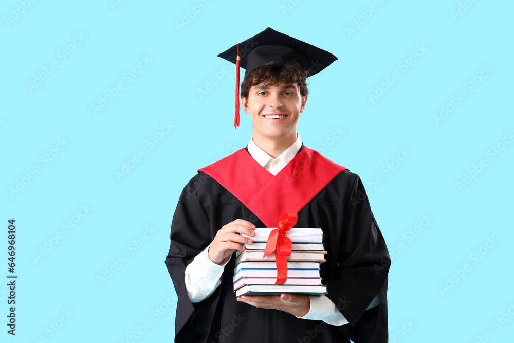 Male graduate student with diploma and books on blue background