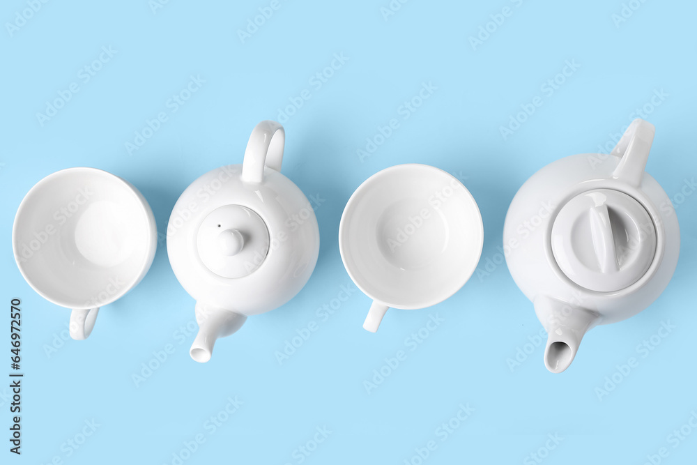 Teapots and cups on color background