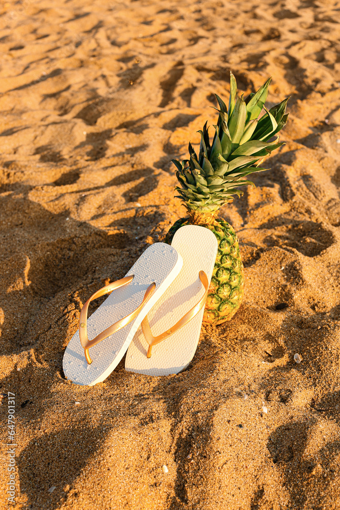Stylish flips flops with pineapple on sand at resort