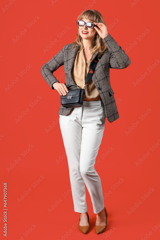 Stylish young woman in fall clothes on red background