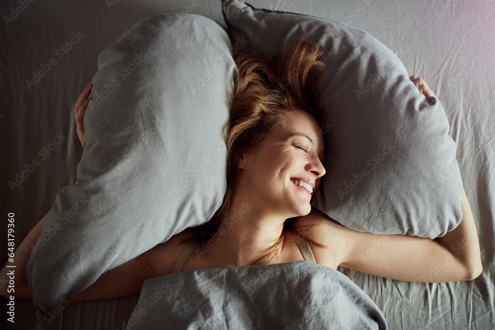 Young Caucasian woman sleeping in her bed and having happy dreams