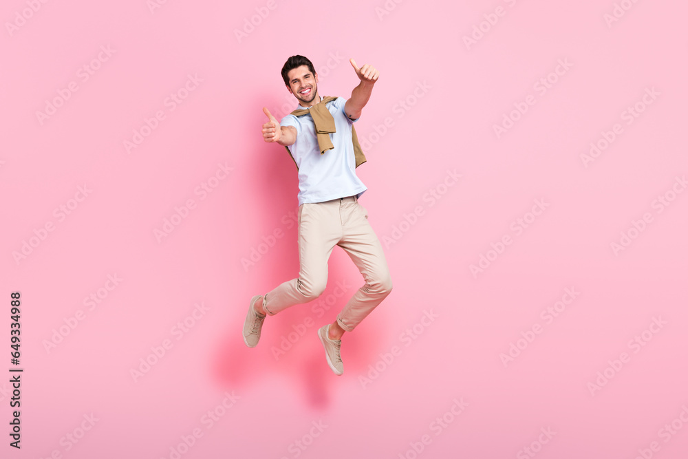 Full body photo of carefree cheerful person jumping hands fingers demonstrate thumb up isolated on pink color background