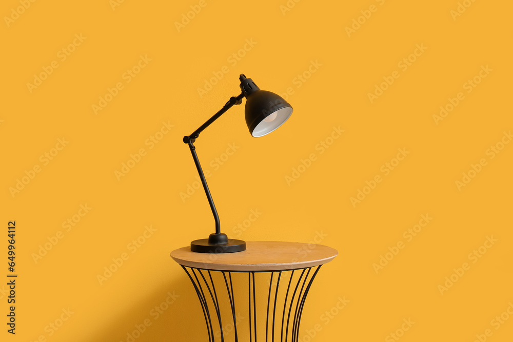 Small table with lamp near yellow wall