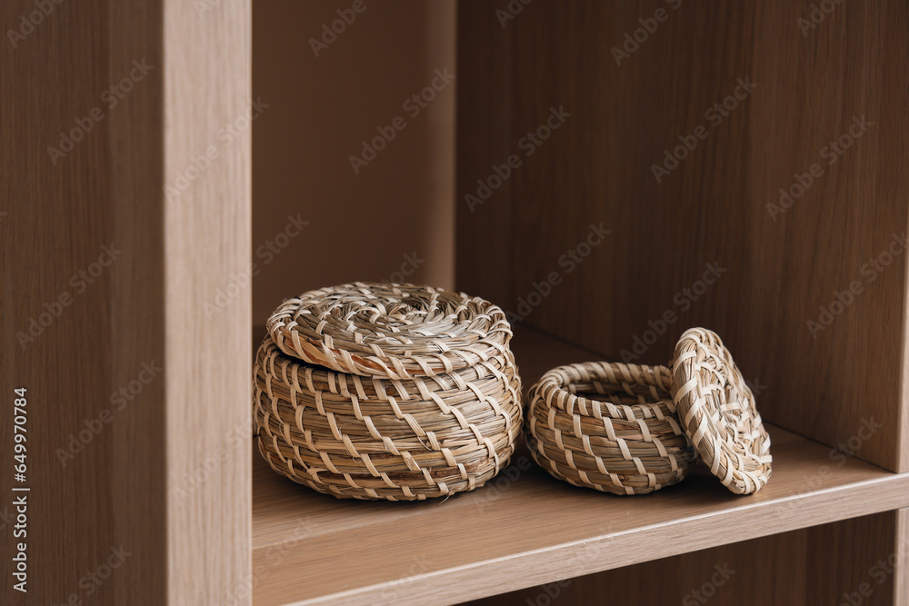 Wooden shelving unit with wicker baskets near beige wall