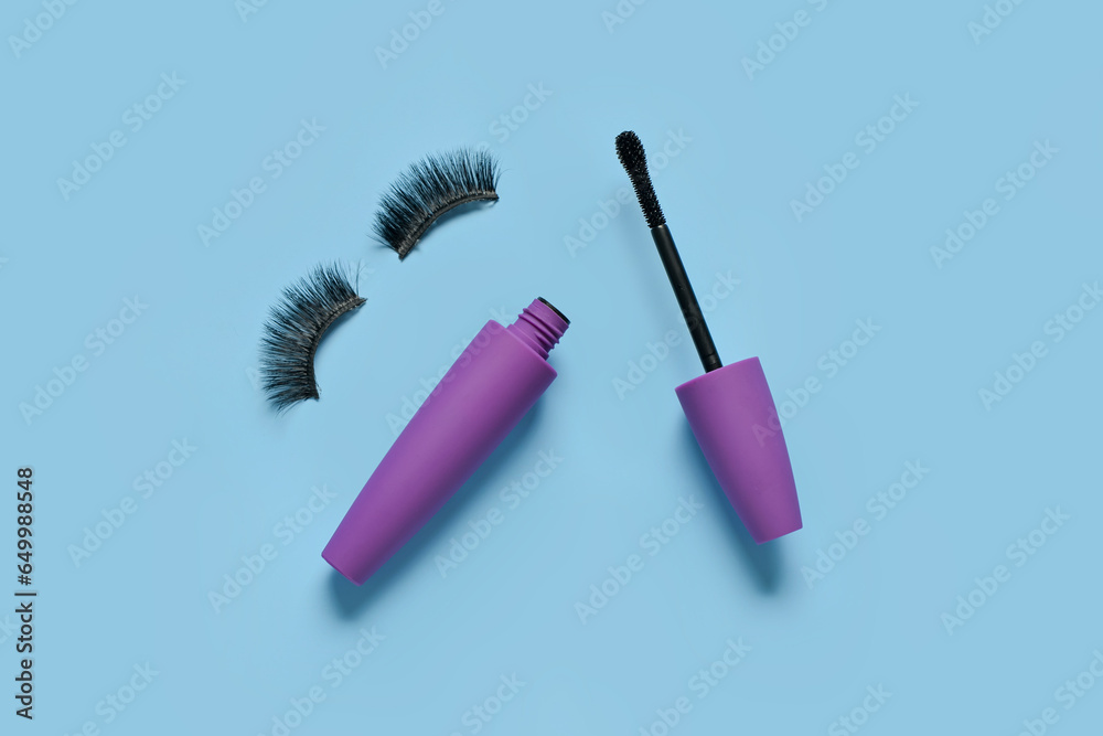 Black mascara in purple tube and fake eyelashes on blue background