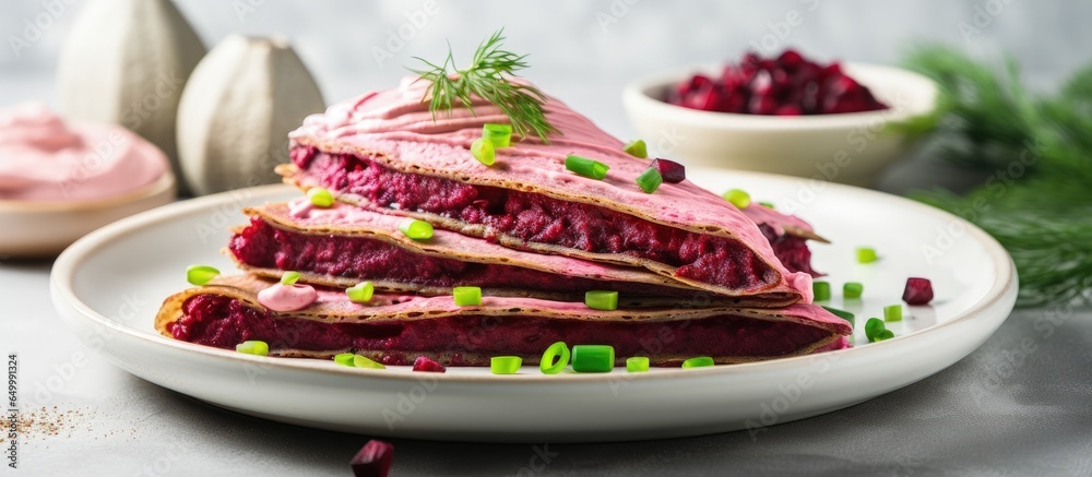 Beetroot pancakes with cream cheese and cucumber on a white plate with a concrete background for pancake day or Maslenitsa