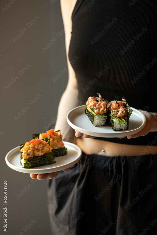 Woman holding plates of japanese hand sushi rolls