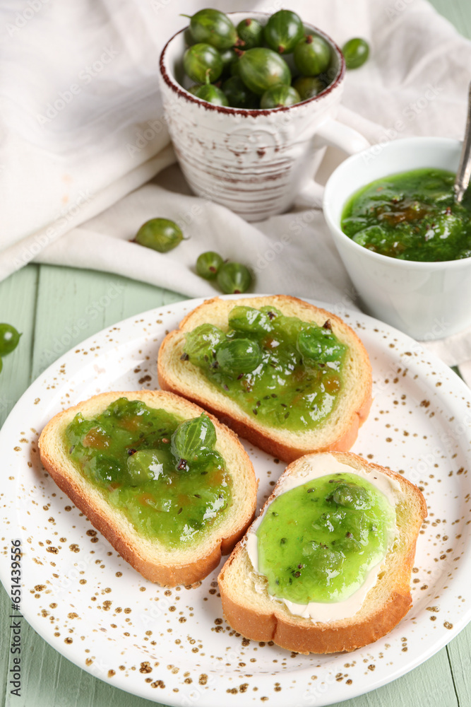 Plate of tasty sandwiches with gooseberry jam on green wooden background