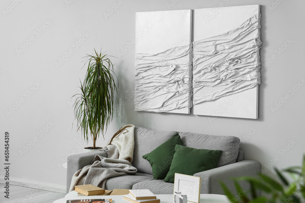 Interior of modern living room with paintings, grey sofa and houseplant