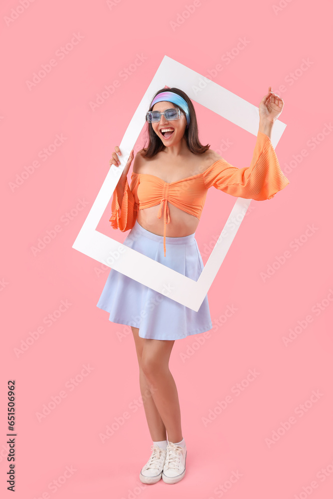 Beautiful young woman with frame on pink background