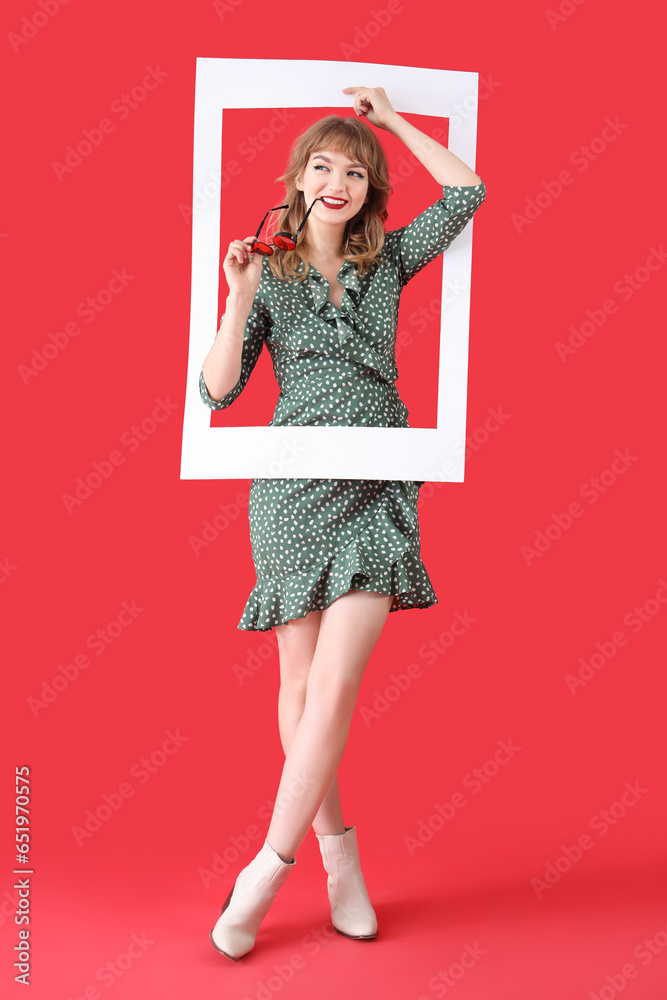 Young woman with sunglasses and frame on red background