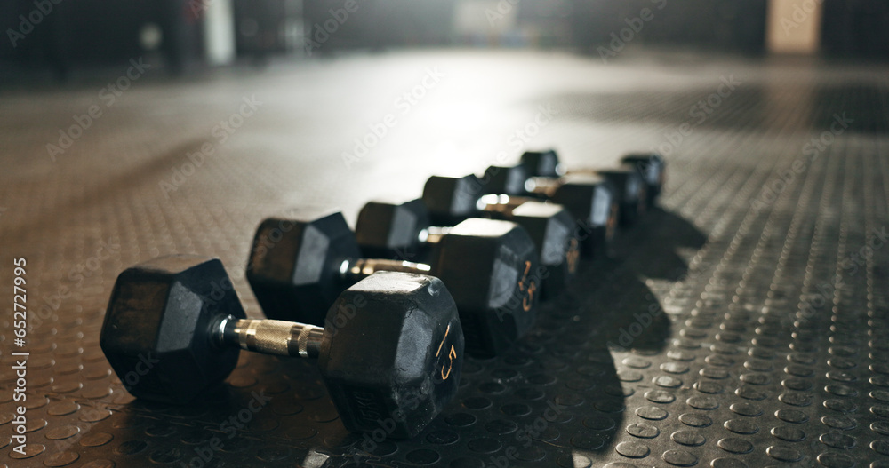 Fitness, background and dumbbells in empty gym for exercise, bodybuilding workout and sports training. Closeup of heavy steel weights, equipment and iron on floor in wellness club for muscle power