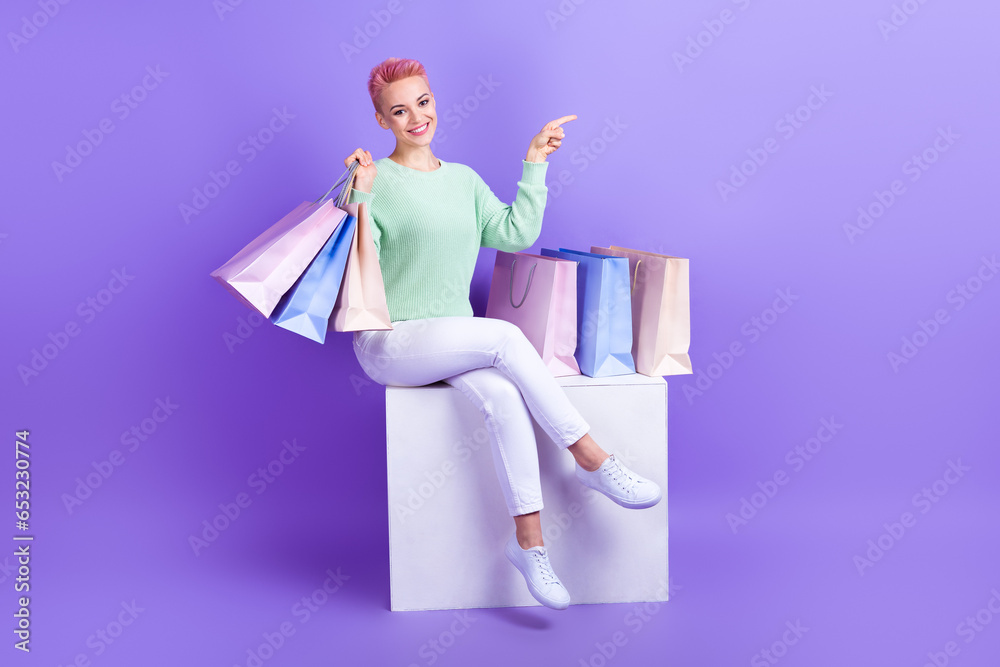 Full length photo of shiny positive girl wear turquoise sweater holding shoppers showing empty space isolated violet color background