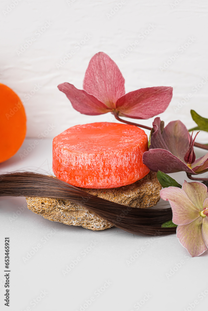 Solid shampoo bars with stones, hair and flowers on table